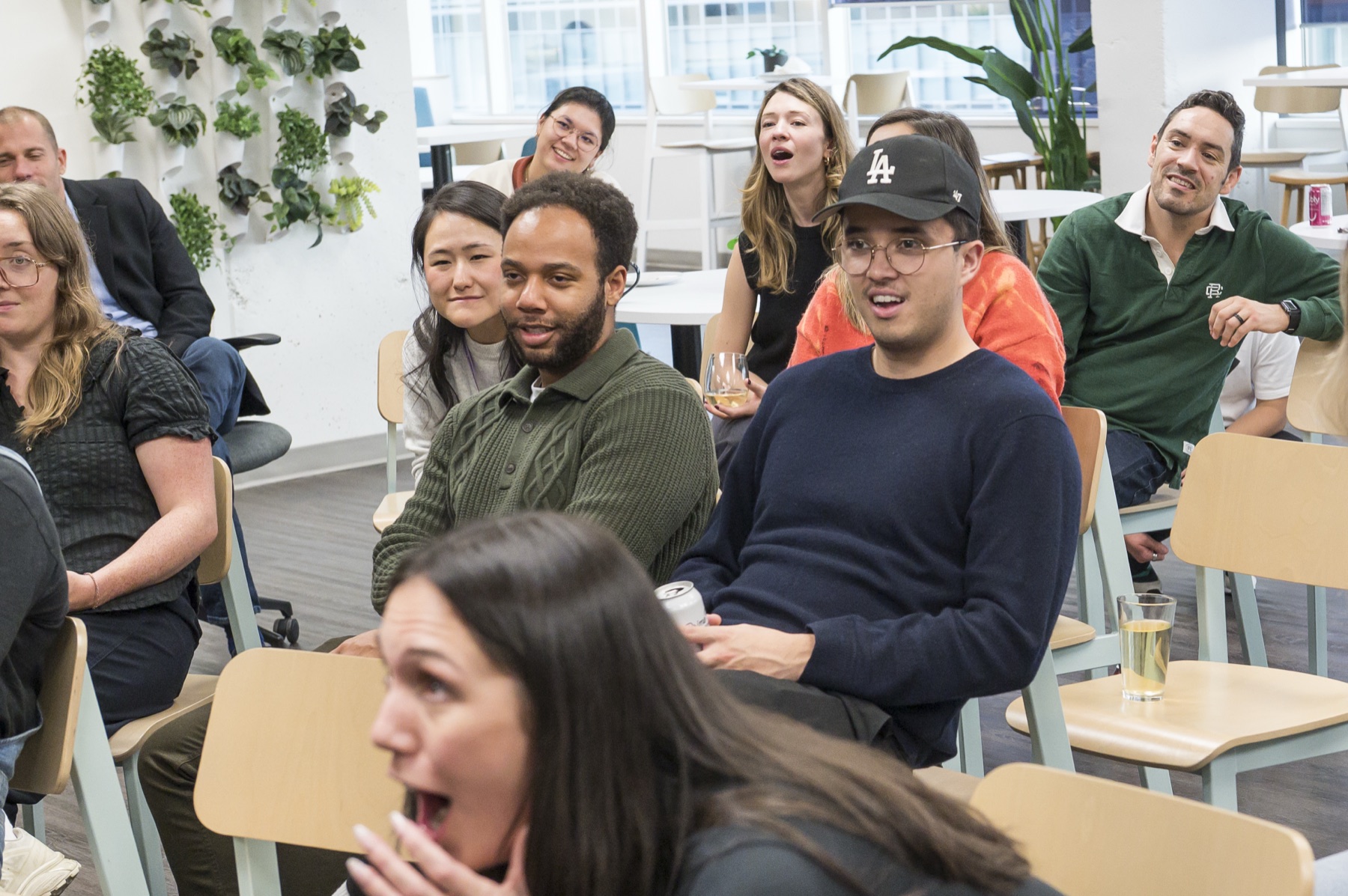 A group of Thinkific employees seated and reacting with surprise during a close-up magic set at their office happy hour