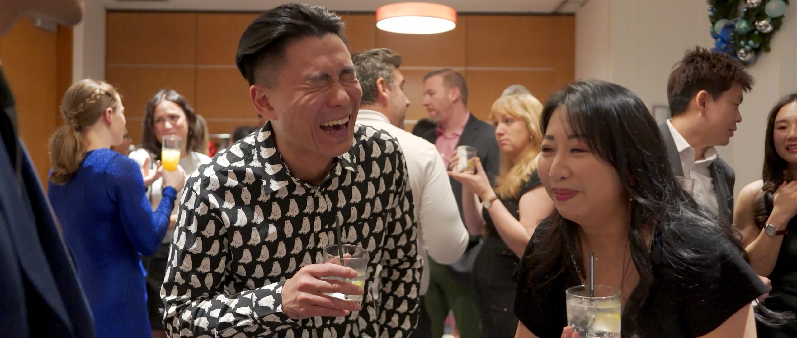 A guest laughing hard during close-up magic at a Vancouver corporate Christmas party