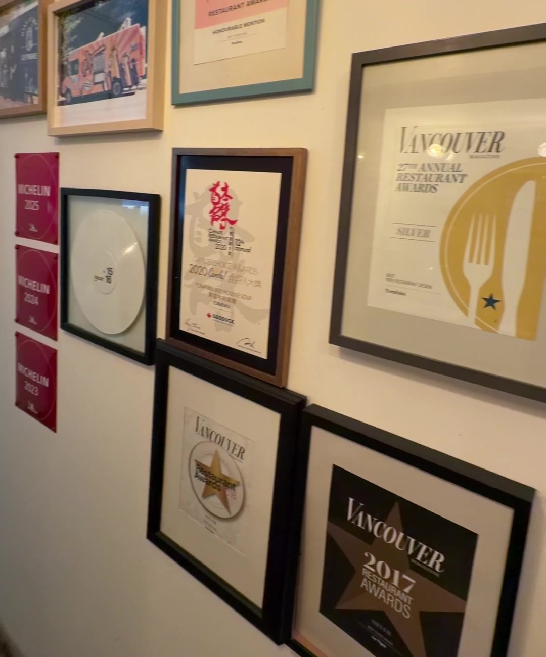 Torafuku's award wall in Vancouver: three red Michelin Guide plaques for 2023, 2024 and 2025 beside framed Vancouver Magazine Restaurant Awards and a Chinese Restaurant Awards certificate