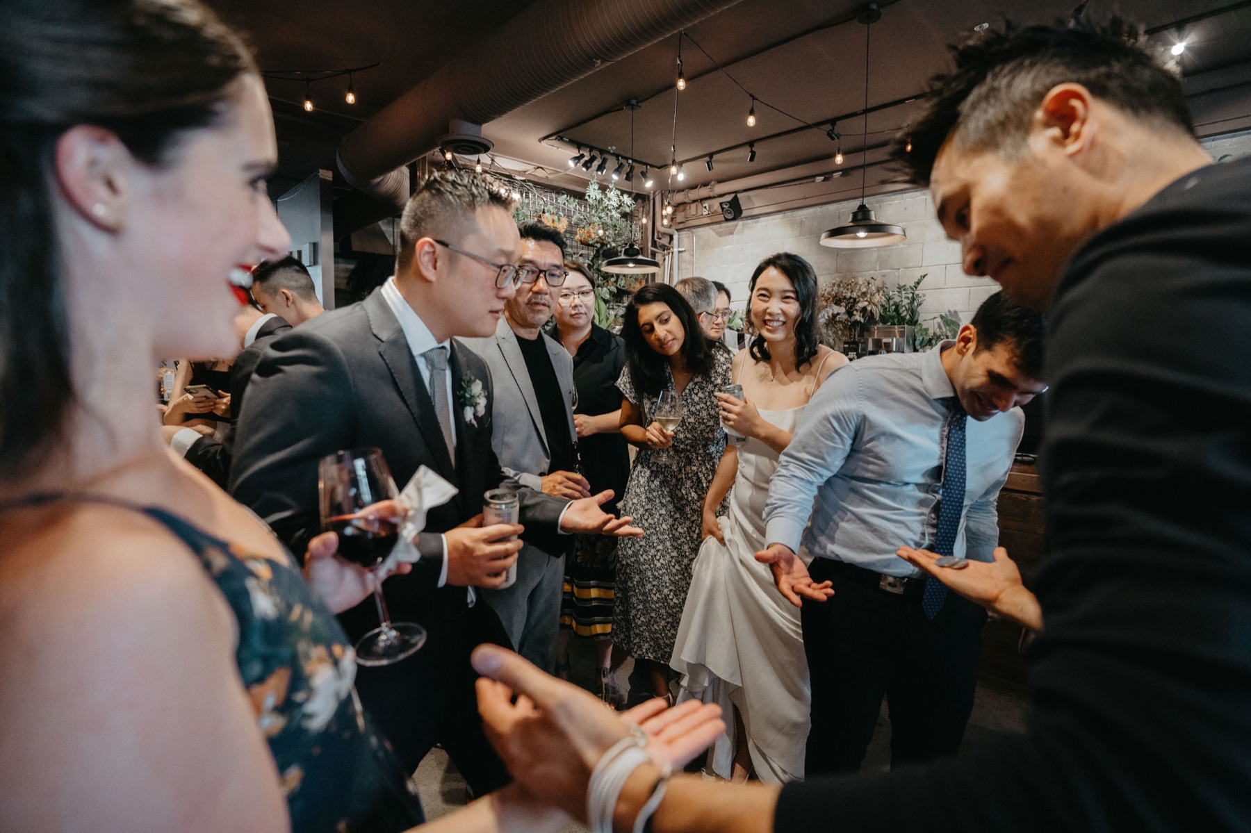 The bride and guests gathered around a coin routine during a Strathcona wedding reception in Vancouver