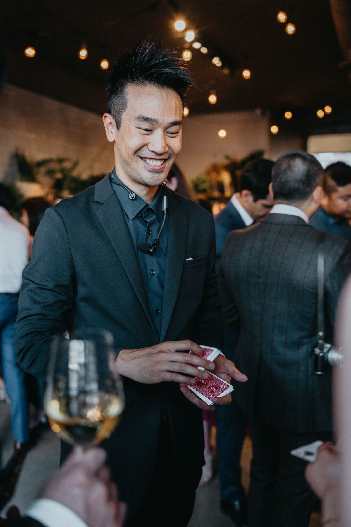 Kel wearing a headset microphone and holding a deck of cards while working the room at a Strathcona wedding