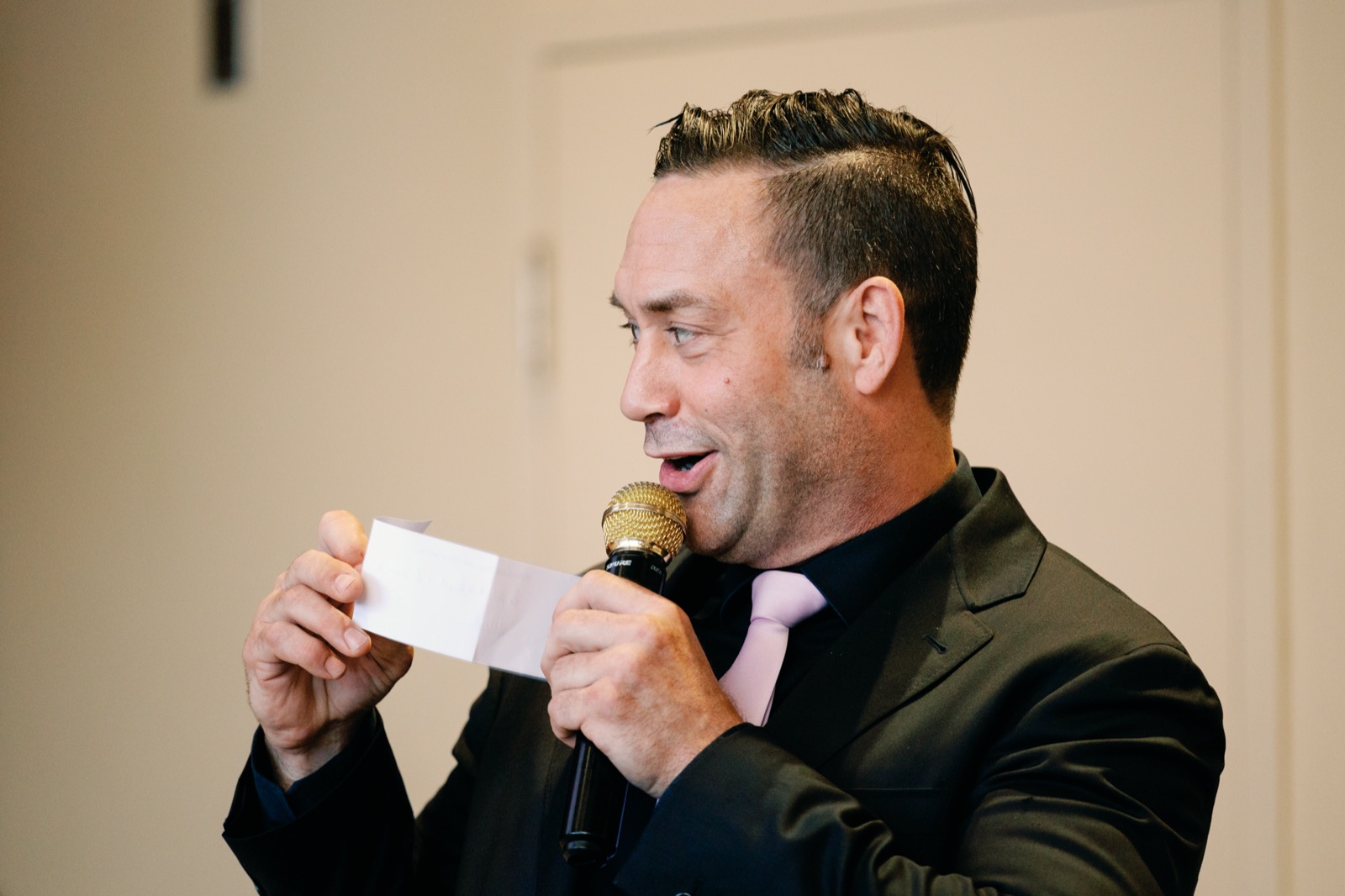 Master of ceremonies reading a guest's card on microphone during an interactive wedding game