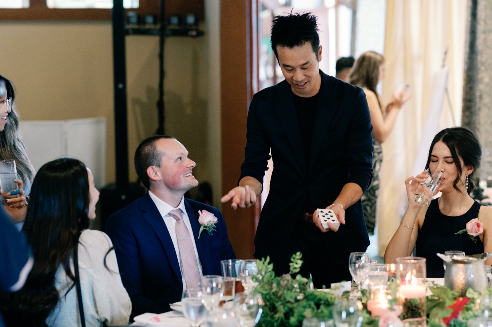 Magician performing close-up card magic for seated guests during dinner at a Vancouver wedding