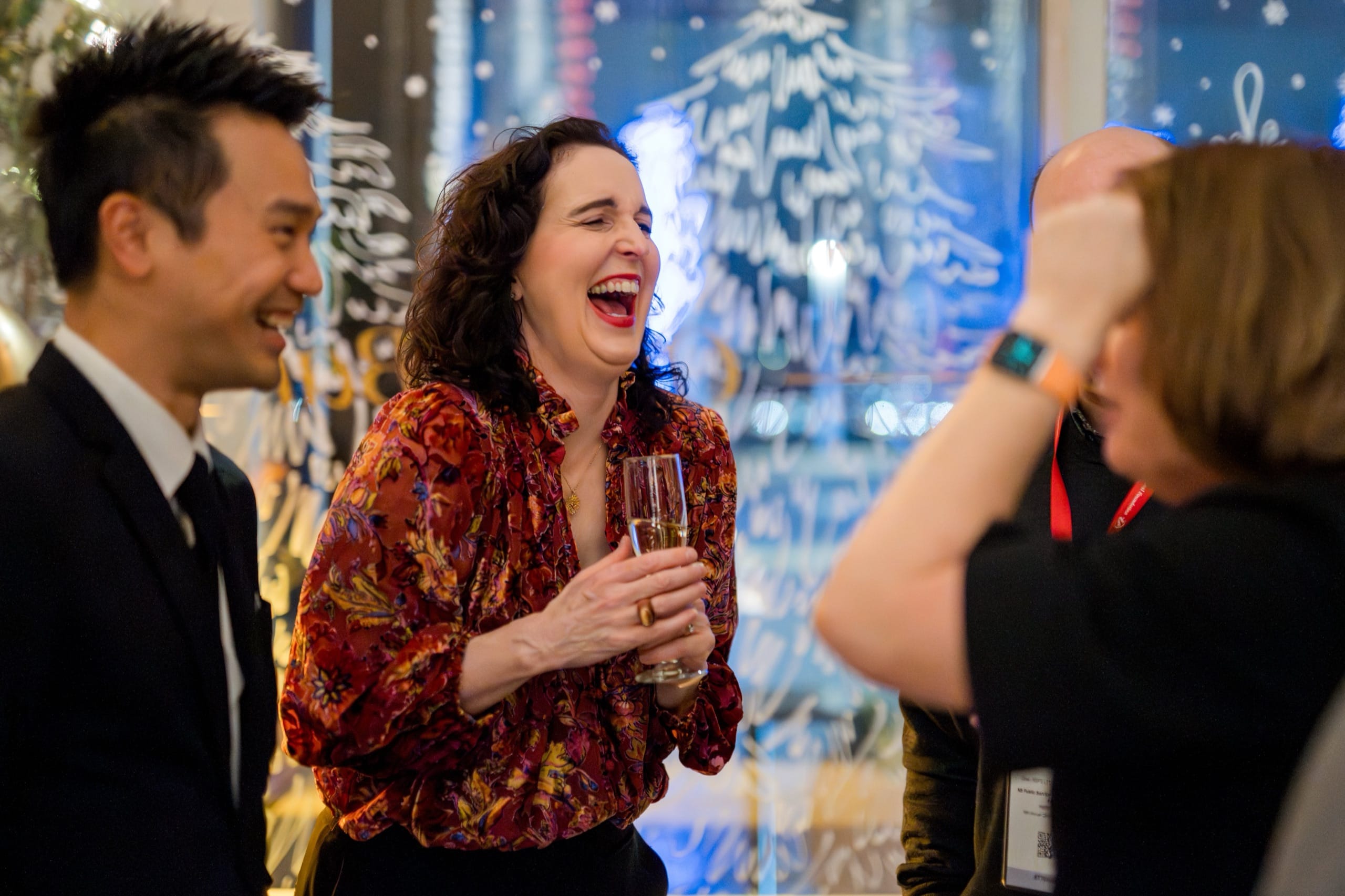 Guests laughing during close-up magic at a Vancouver holiday party