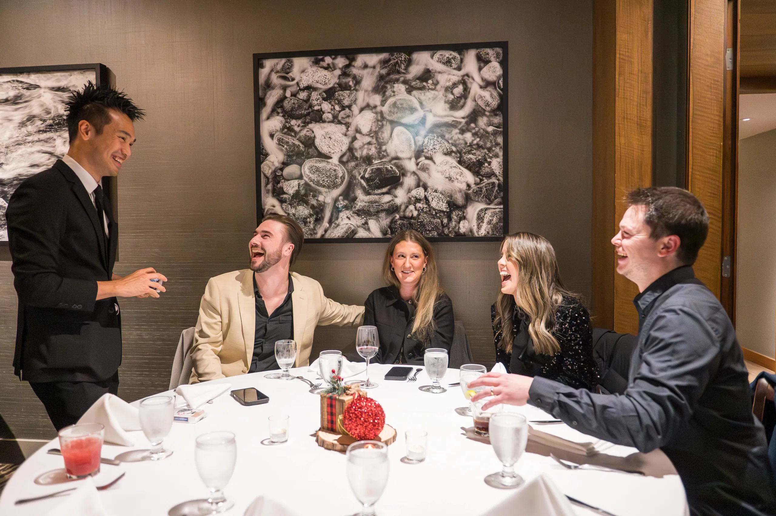A table of corporate guests laughing together during close-up magic at a Vancouver event