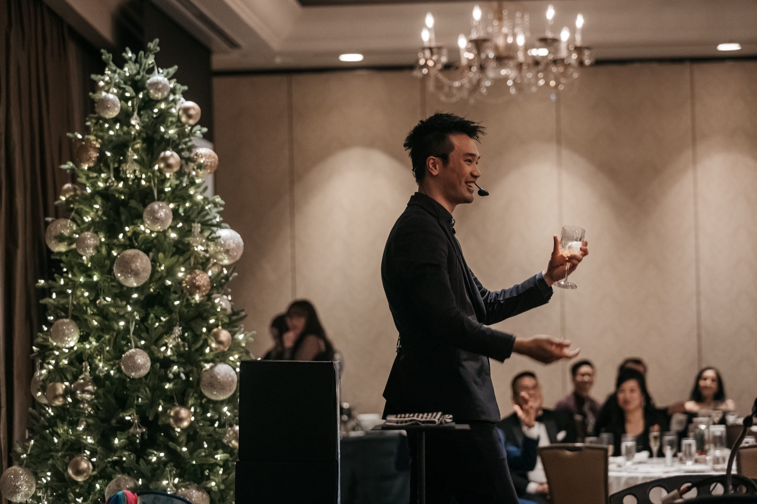 A magic effect performed with a wine glass beside a Christmas tree at a Vancouver holiday party